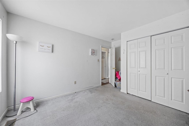 unfurnished bedroom featuring light carpet and a closet