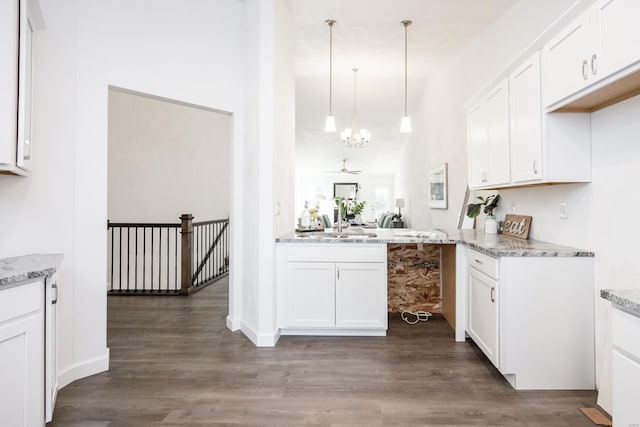 kitchen featuring light stone counters, pendant lighting, white cabinets, a chandelier, and dark hardwood / wood-style floors