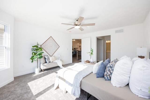 carpeted bedroom with ensuite bathroom and ceiling fan