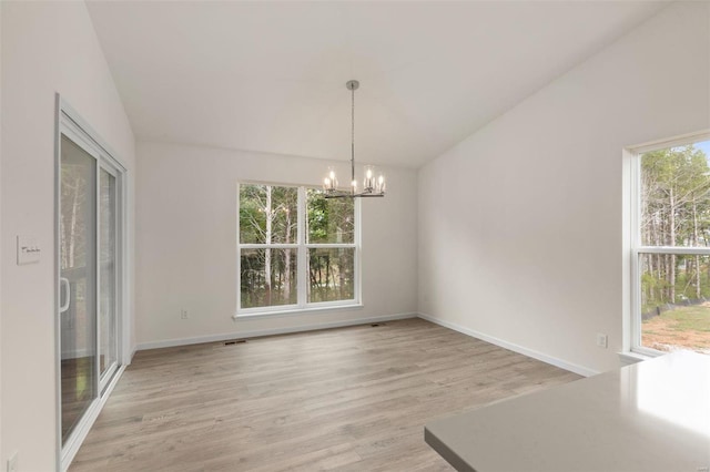 unfurnished dining area featuring light wood-type flooring, an inviting chandelier, and vaulted ceiling