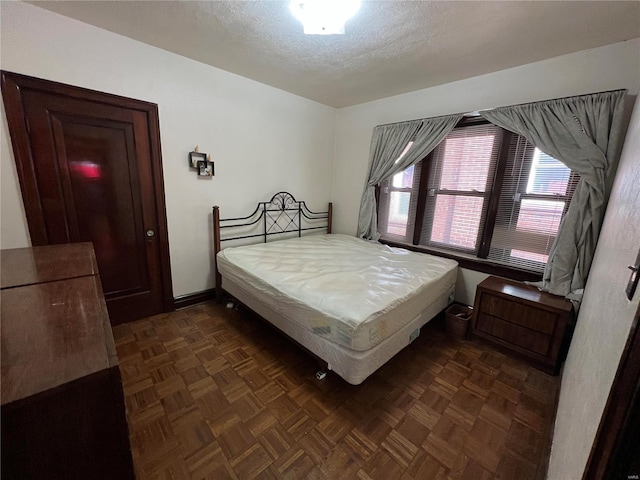 bedroom featuring dark parquet flooring and a textured ceiling