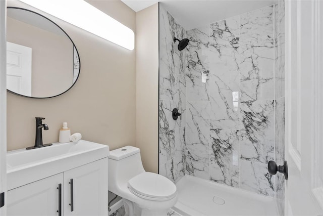 bathroom featuring a tile shower, vanity, and toilet