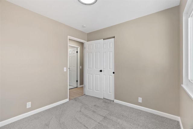 unfurnished bedroom featuring light colored carpet and a closet