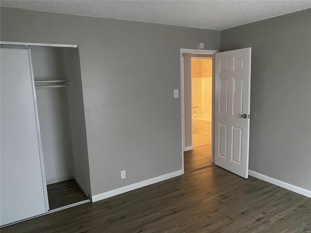 unfurnished bedroom featuring a textured ceiling, dark hardwood / wood-style floors, and a closet