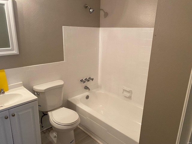 full bathroom featuring toilet, vanity, tile walls, and  shower combination