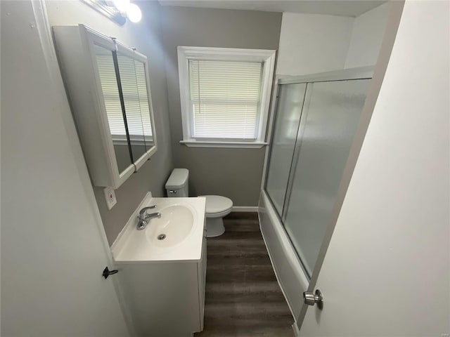 full bathroom with toilet, bath / shower combo with glass door, hardwood / wood-style floors, and vanity