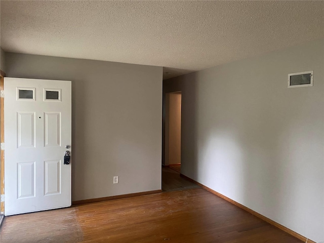 empty room with wood-type flooring and a textured ceiling