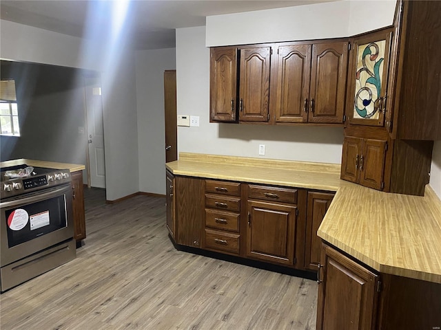 kitchen with stainless steel electric stove, dark brown cabinets, and light wood-type flooring