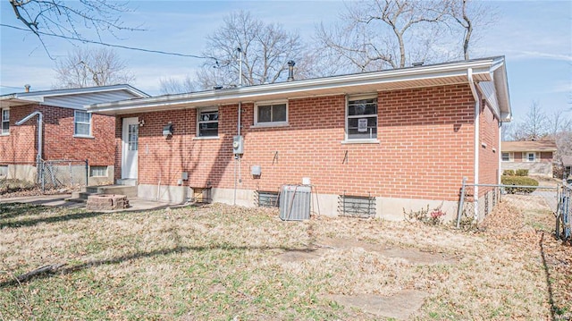 rear view of property featuring central AC unit and a yard