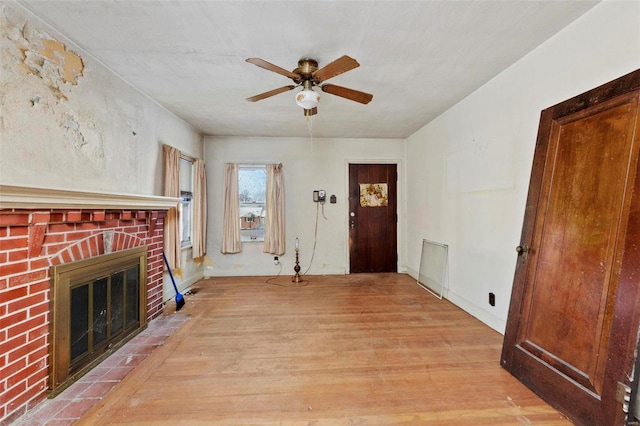 unfurnished living room with ceiling fan, a fireplace, and light hardwood / wood-style flooring