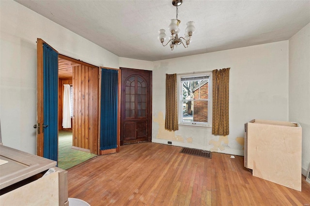 unfurnished room with wood-type flooring, an inviting chandelier, and a textured ceiling