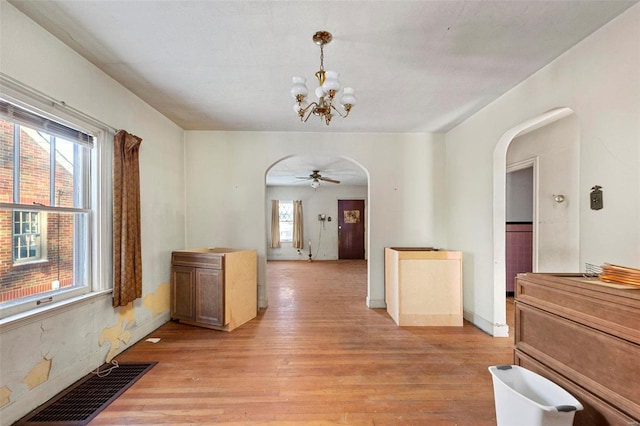 corridor with a wealth of natural light, light hardwood / wood-style flooring, and an inviting chandelier