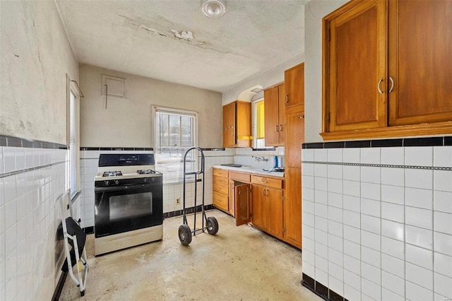 kitchen featuring gas range and tile walls