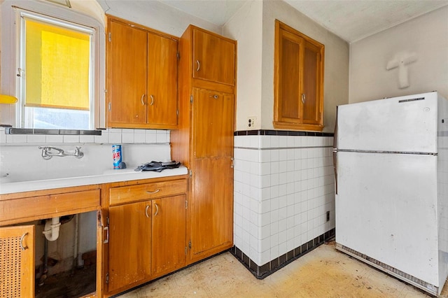 kitchen with tile walls, sink, and white refrigerator