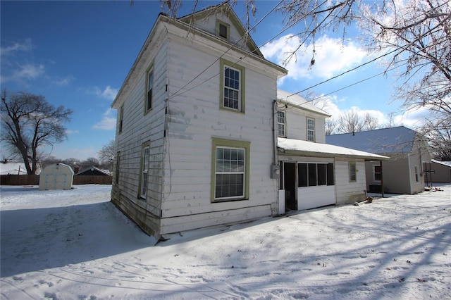 snow covered house featuring a storage unit