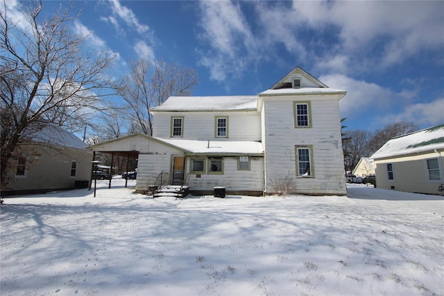 snow covered house featuring a carport