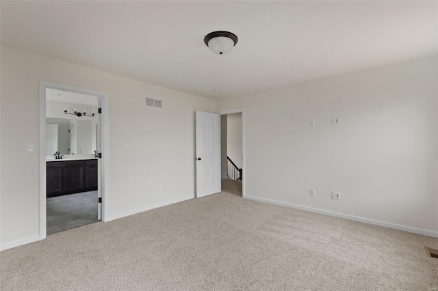 unfurnished bedroom with ensuite bathroom, sink, and light carpet