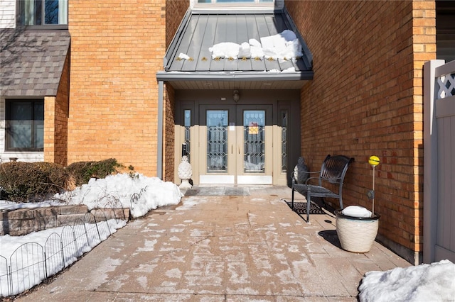 snow covered property entrance featuring french doors