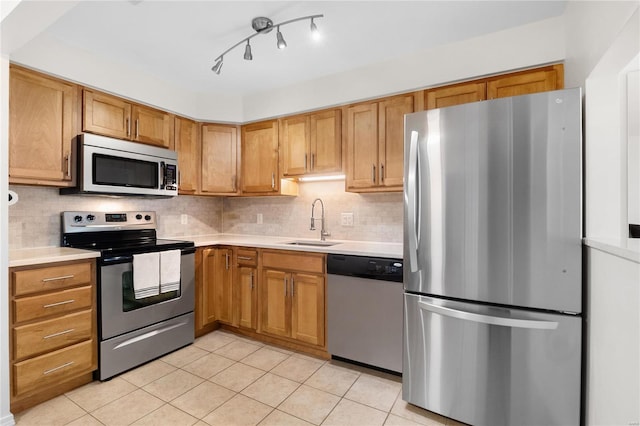 kitchen with appliances with stainless steel finishes, backsplash, sink, and light tile patterned floors