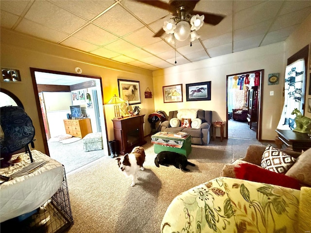 carpeted living room with a drop ceiling and ceiling fan