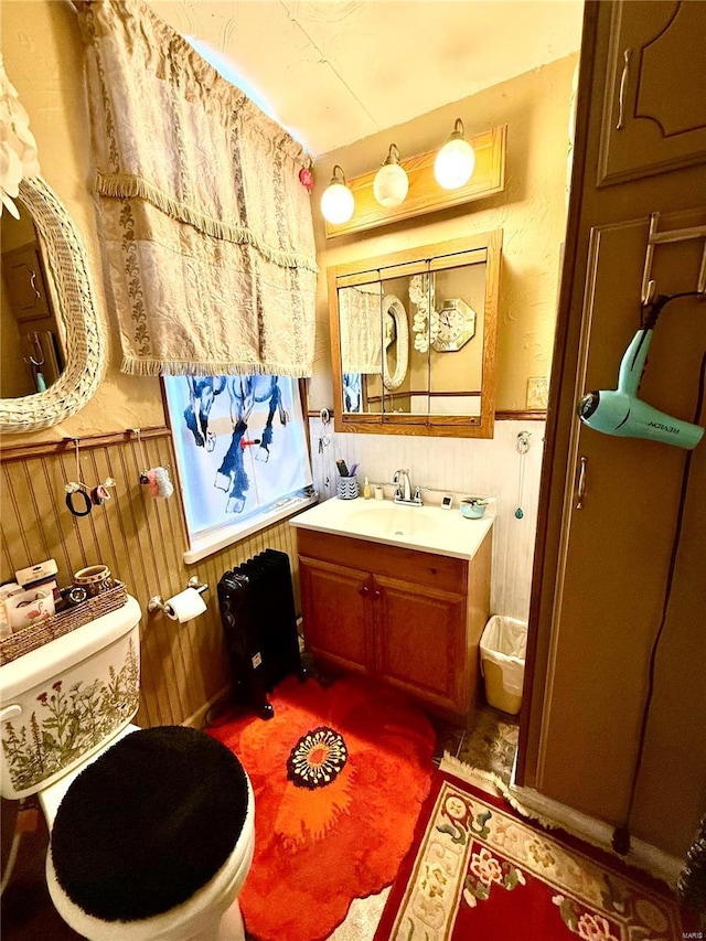 bathroom with vanity, wood walls, and toilet