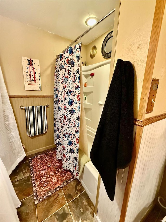 bathroom featuring wooden walls and shower / bath combo with shower curtain