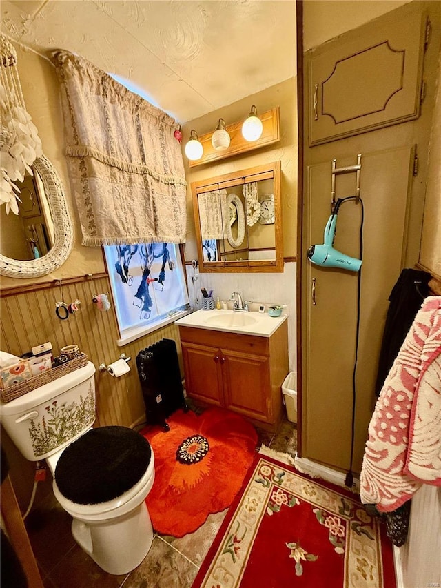 bathroom featuring wooden walls, vanity, and toilet