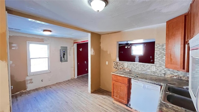 kitchen with backsplash, electric panel, dishwasher, and light hardwood / wood-style floors