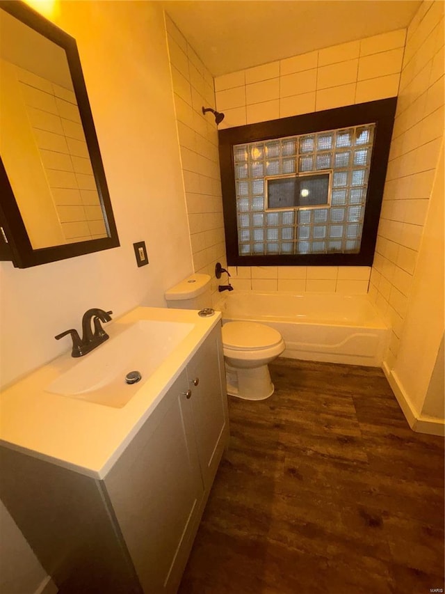 full bathroom featuring hardwood / wood-style flooring, vanity, tiled shower / bath, and toilet