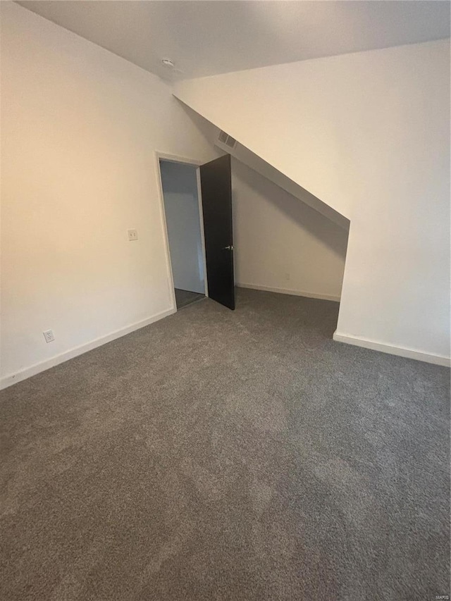 carpeted empty room with vaulted ceiling