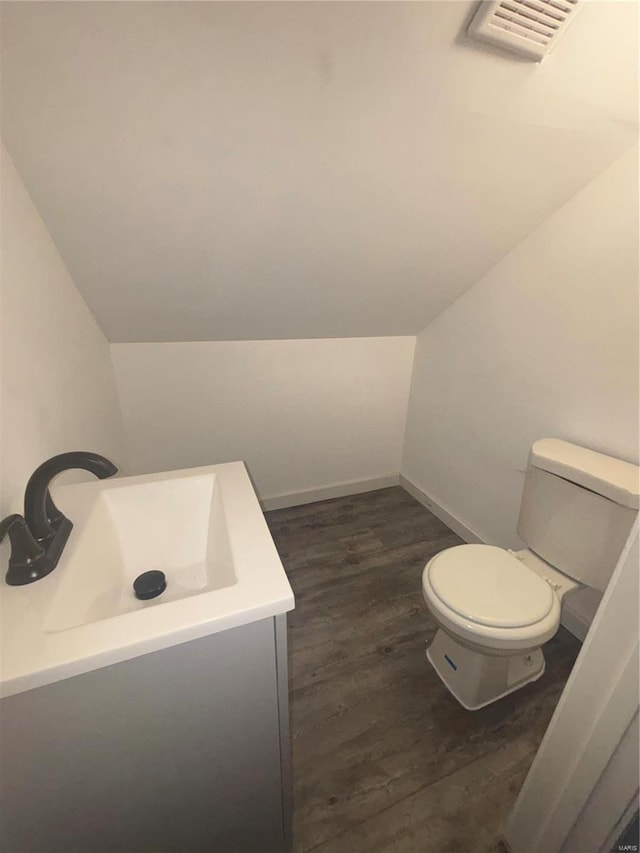 bathroom with lofted ceiling, vanity, toilet, and hardwood / wood-style floors