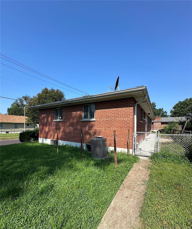 view of side of home with central AC and a yard