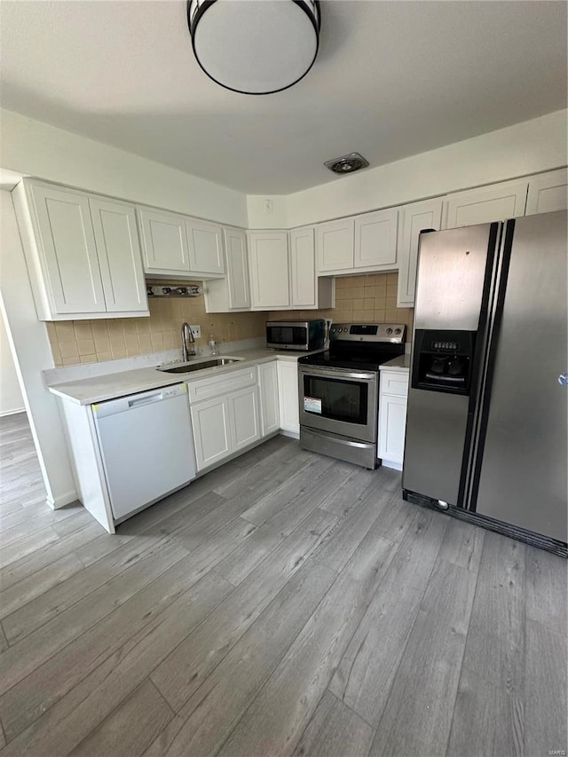 kitchen featuring white cabinetry, sink, stainless steel appliances, and light hardwood / wood-style floors