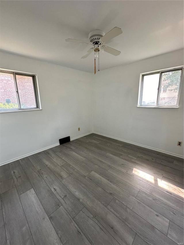 spare room with a wealth of natural light, ceiling fan, and dark hardwood / wood-style floors