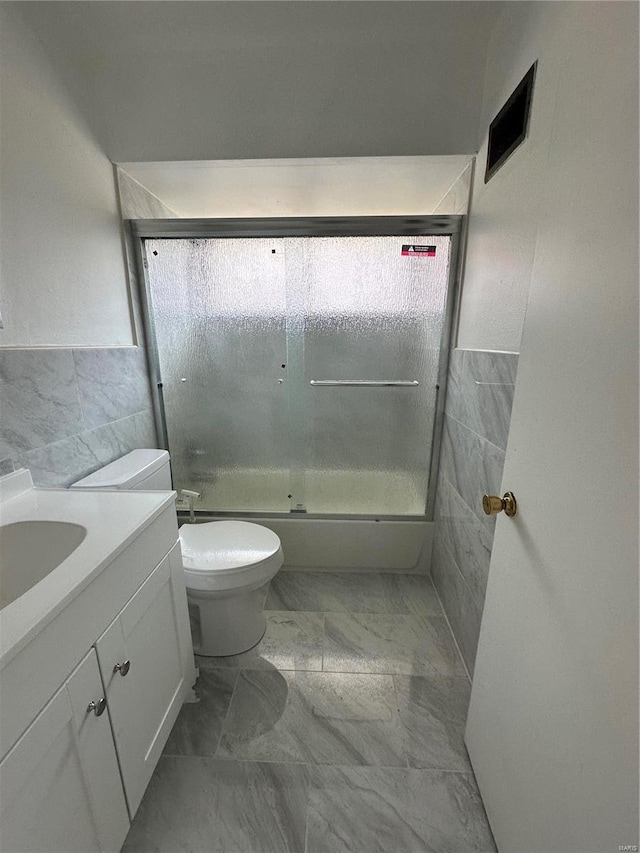 bathroom featuring vanity, toilet, and tile walls