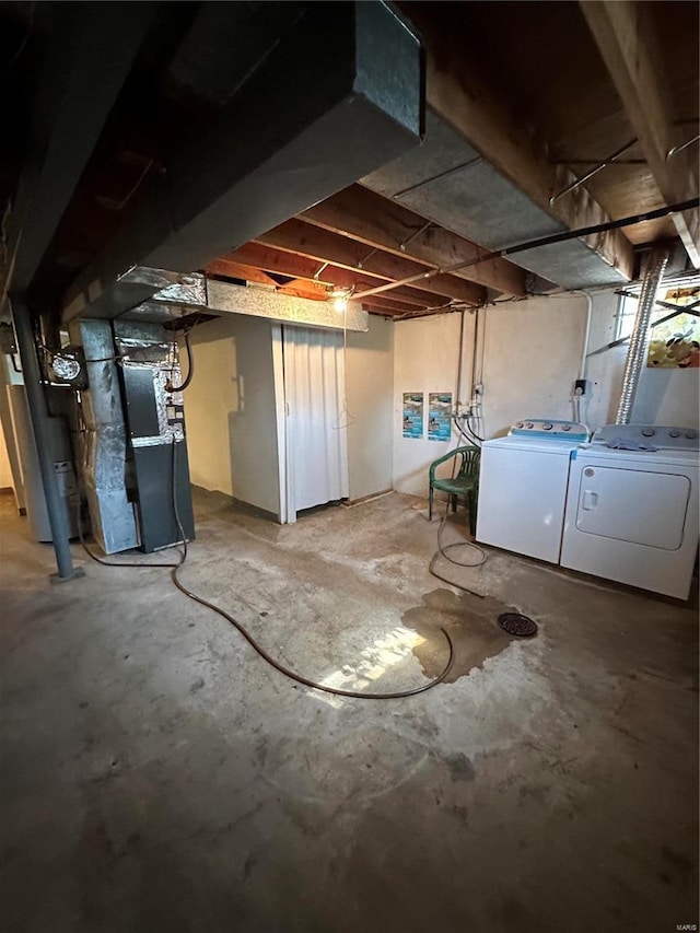 basement with heating unit, water heater, and washing machine and clothes dryer