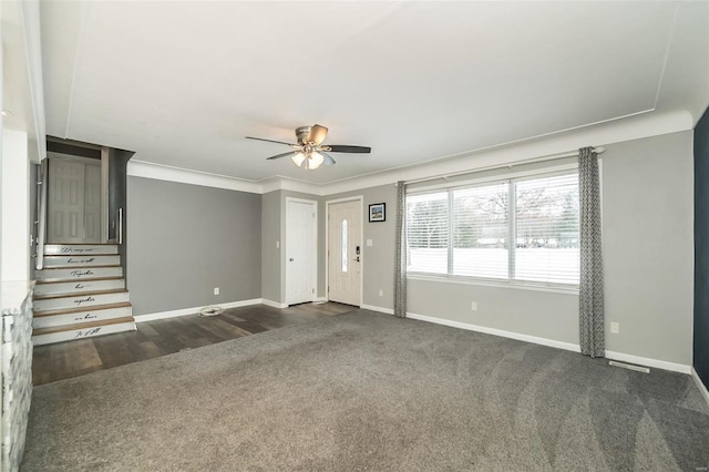 foyer entrance with ceiling fan and dark carpet