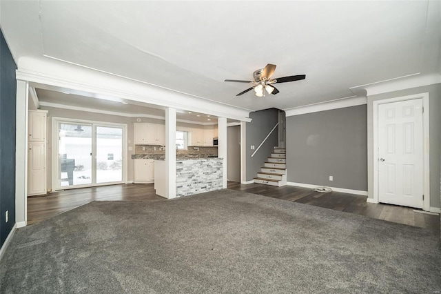 unfurnished living room featuring dark colored carpet, ceiling fan, and crown molding