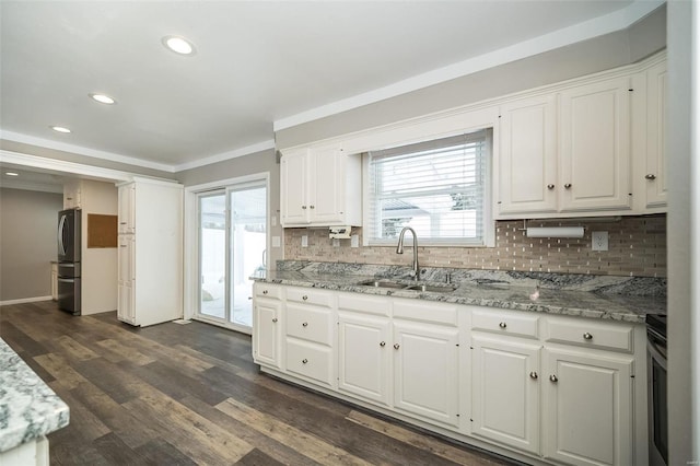 kitchen with light stone counters, white cabinetry, a healthy amount of sunlight, and sink