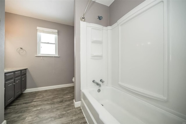 full bathroom with hardwood / wood-style flooring, toilet, vanity, and washtub / shower combination