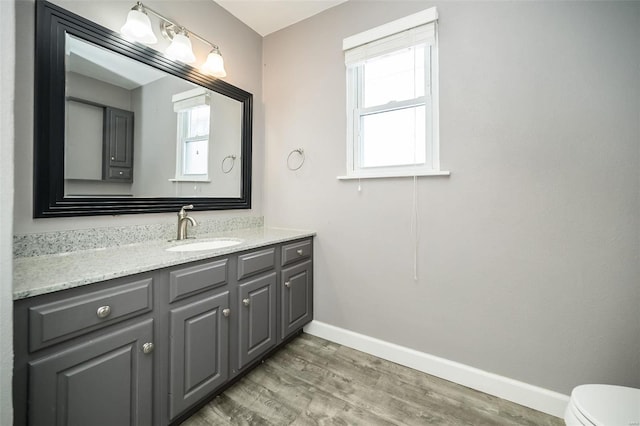 bathroom with wood-type flooring, vanity, toilet, and plenty of natural light