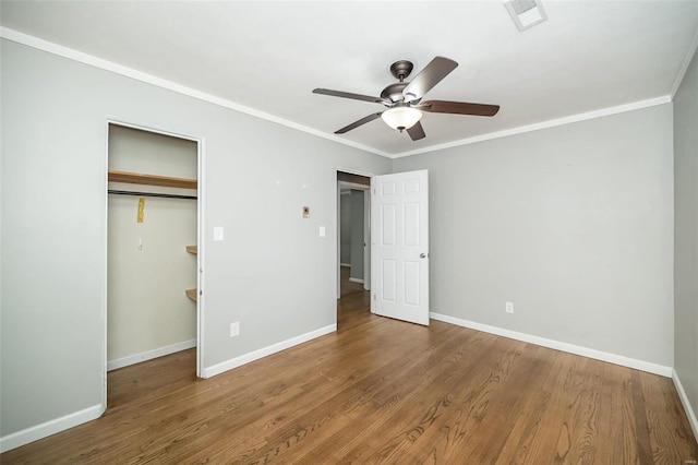 unfurnished bedroom featuring ceiling fan, wood-type flooring, ornamental molding, and a closet