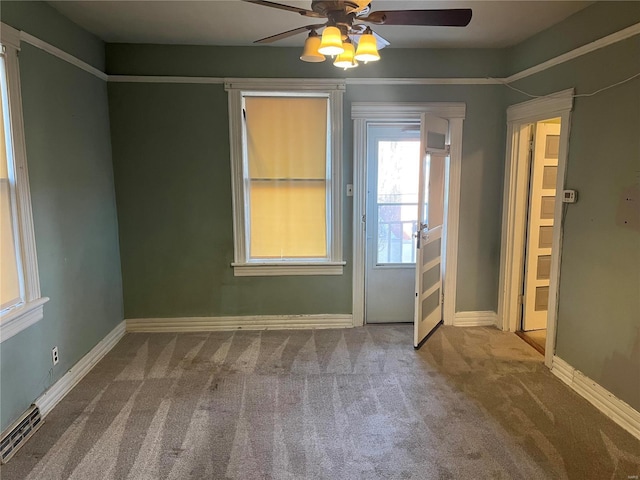 carpeted spare room featuring a ceiling fan, visible vents, and baseboards