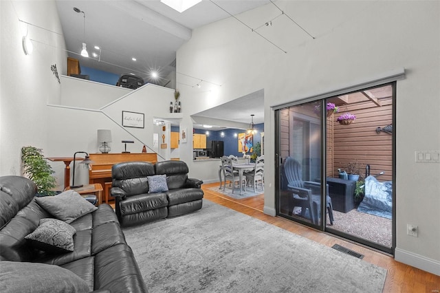 living area with visible vents, baseboards, stairs, a high ceiling, and wood finished floors