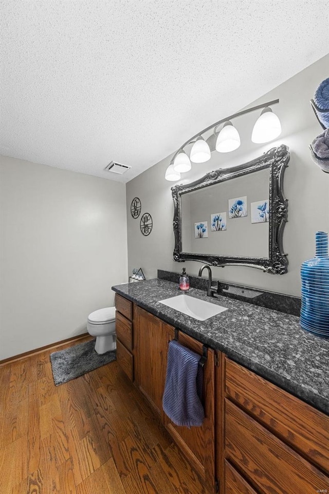 bathroom featuring visible vents, a textured ceiling, wood finished floors, and vanity