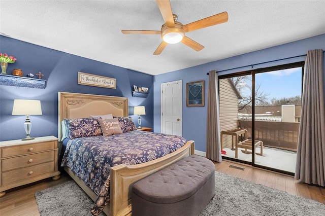 bedroom with a ceiling fan, wood finished floors, visible vents, a textured ceiling, and access to outside