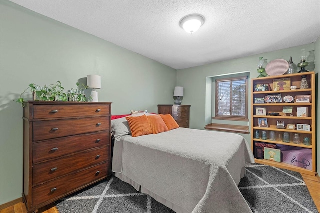 bedroom with a textured ceiling and dark wood finished floors