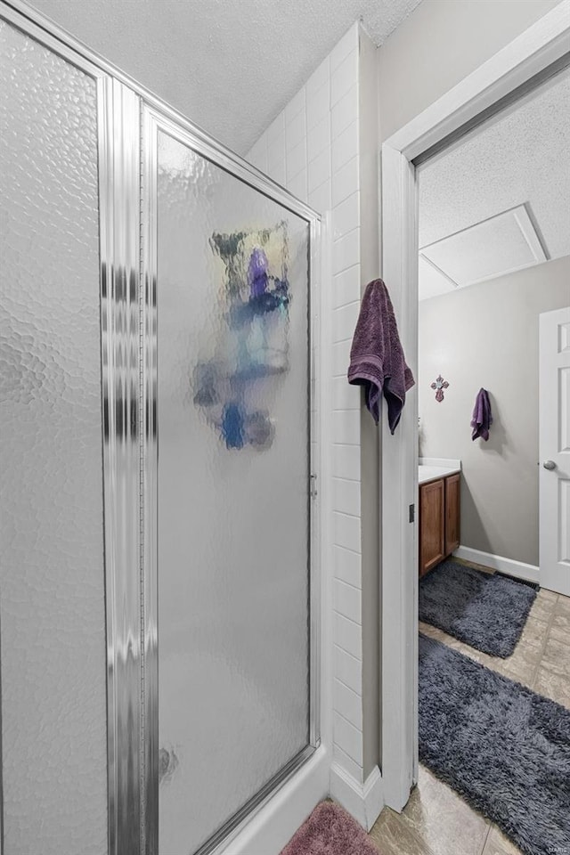 bathroom with vanity, baseboards, a stall shower, and a textured ceiling