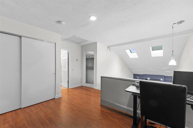 home office with visible vents, a textured ceiling, wood finished floors, a skylight, and baseboards