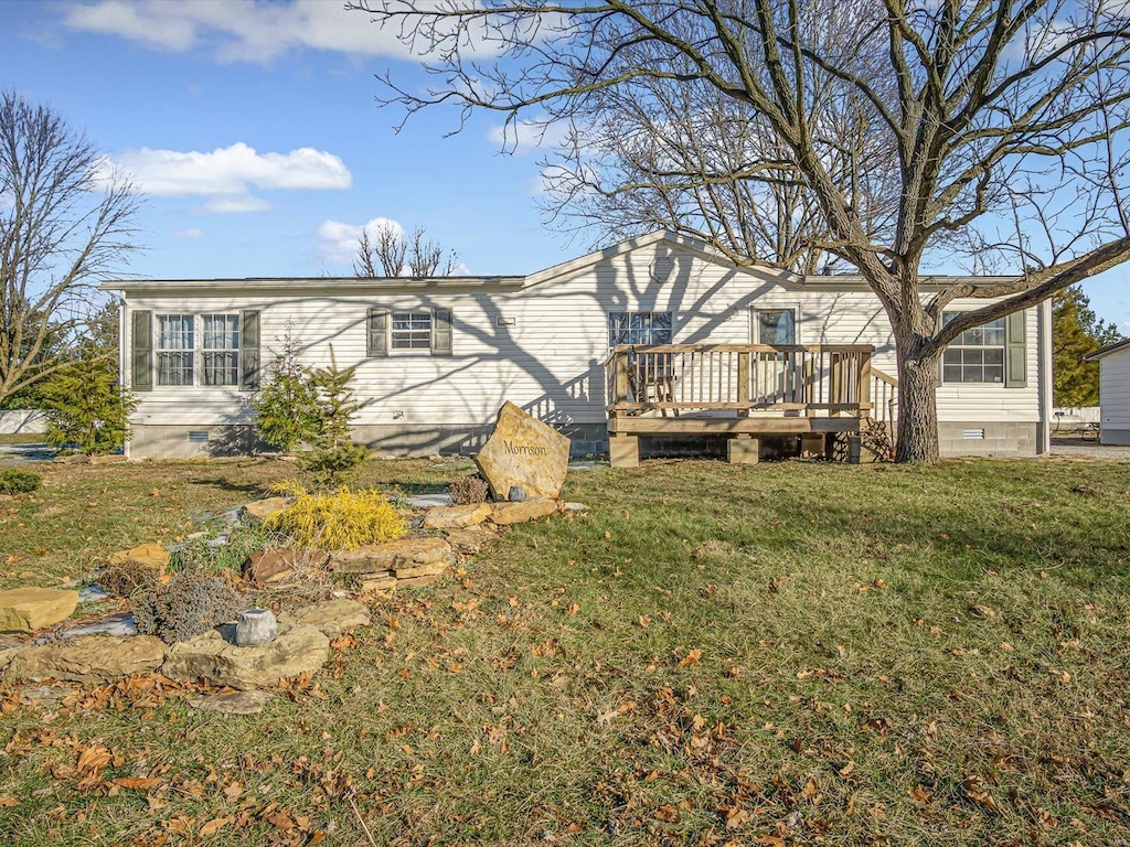 rear view of property with a wooden deck and a lawn